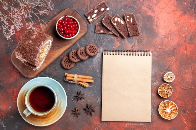 Vista superior de la taza de té con rollo de galletas sobre una superficie oscura