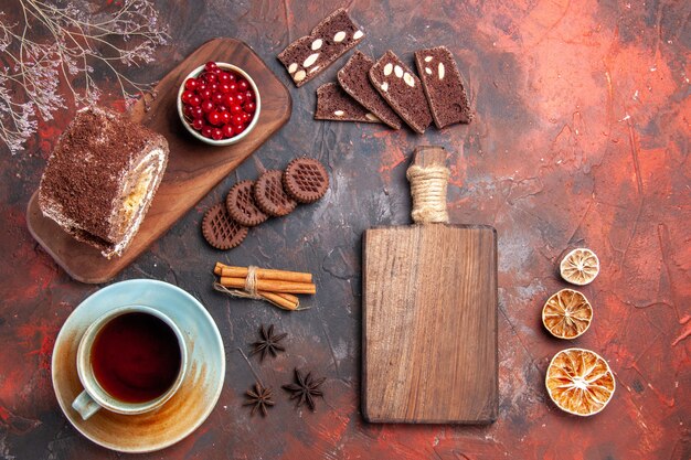 Vista superior de la taza de té con rollo de galletas sobre una superficie oscura