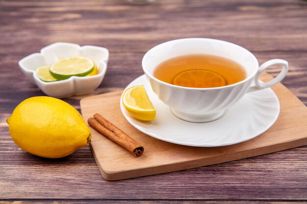 Vista superior de una taza de té en la tabla de cocina de madera con rama de canela y limón sobre madera