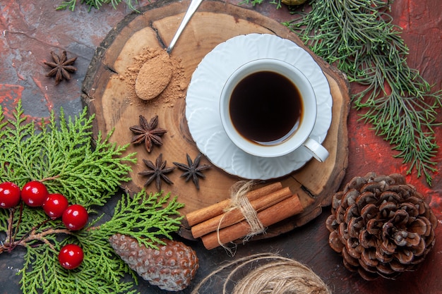 Vista superior de una taza de té en el tablero de madera, palitos de canela, piña de anís sobre fondo oscuro