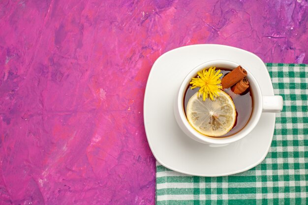 Vista superior de la taza de té en una toalla verde pelada con limón y lima canela en rosa