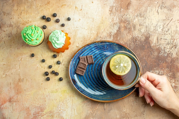 Vista superior de la taza de té con tortas dulces sobre fondo marrón