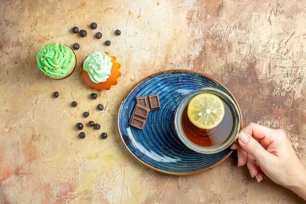 Vista superior de la taza de té con tortas dulces sobre fondo marrón