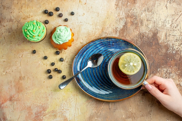 Vista superior de la taza de té con tortas dulces sobre fondo marrón