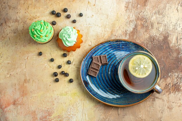 Vista superior de la taza de té con tortas dulces sobre fondo marrón