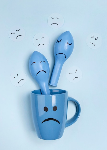 Vista superior de taza triste con globos con ceño fruncido para el lunes azul