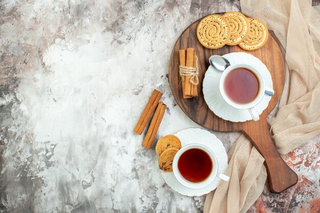 Vista superior de tazas de té con galletas dulces y galletas en el fondo claro romper pastel de azúcar ceremonia pastel color café