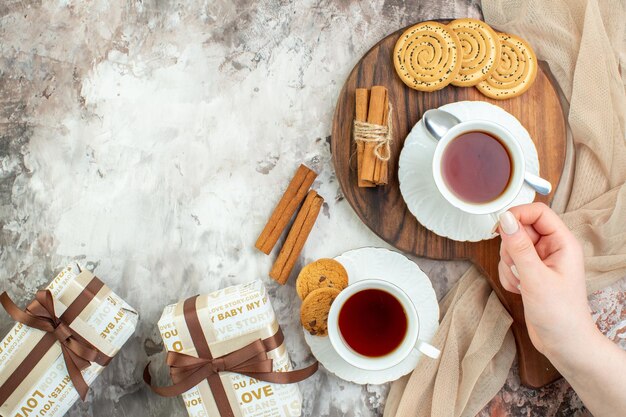 Vista superior tazas de té con galletas dulces y regalos sobre fondo claro color ceremonia romper pastel pastel café azúcar