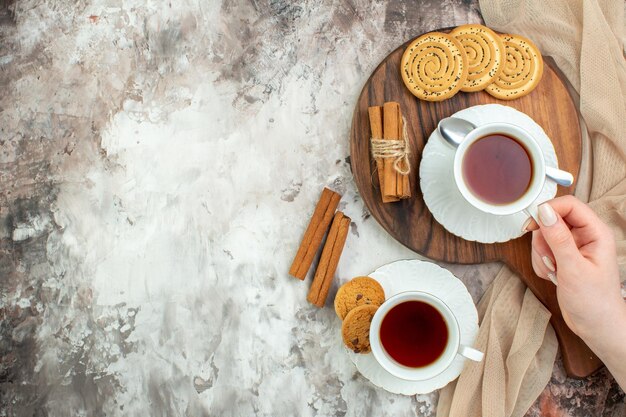 Vista superior tazas de té con galletas dulces sobre fondo claro color ceremonia pastel café azúcar descanso