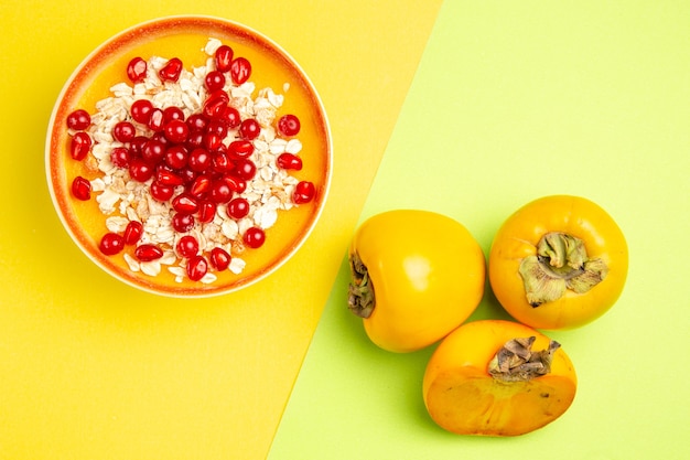 Foto gratuita vista superior tazón de avena de avena con grosellas rojas granadas caquis