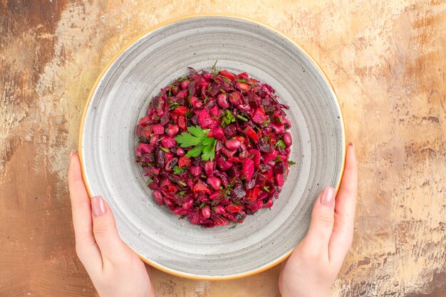 Vista superior del tazón de fuente de una ensalada roja con verduras sobre un fondo de madera