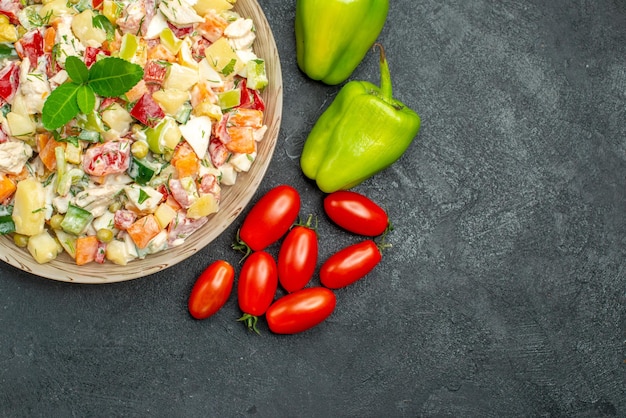 Vista superior del tazón de fuente de ensalada de verduras con pimientos y tomates cherry sobre fondo gris