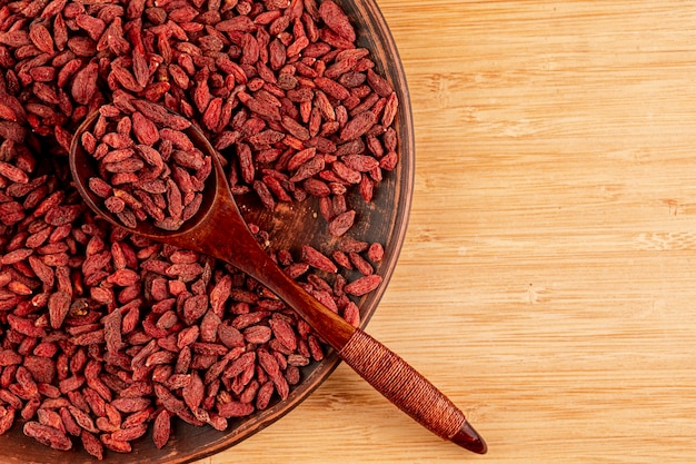 Foto gratuita vista superior del tazón grande con bayas de goji y fondo de madera