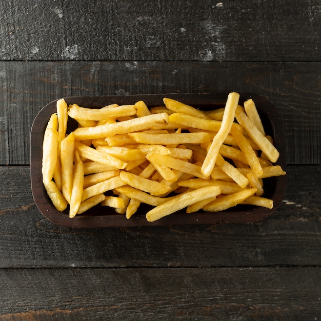 Vista superior del tazón de papas fritas en la superficie de madera