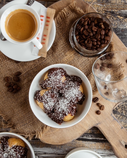 Vista superior del tazón profiterole cubierto con salsa de chocolate con chispitas de coco