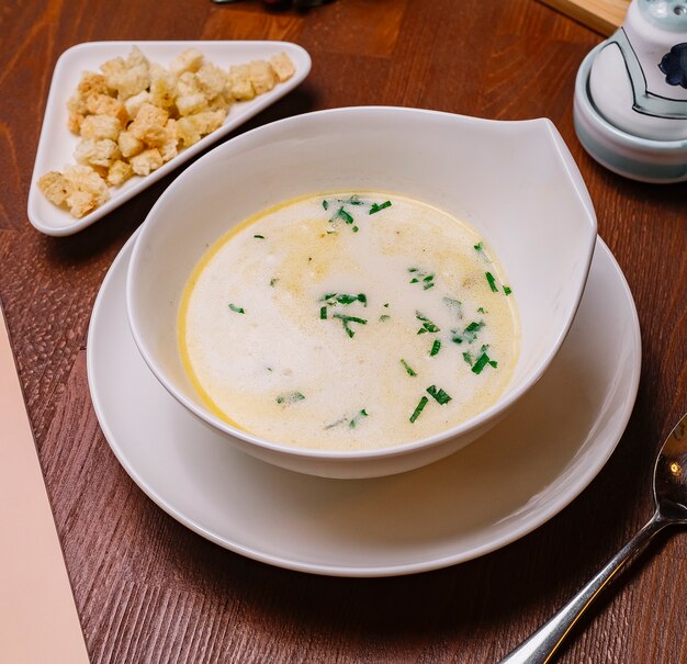 Vista superior del tazón de sopa de pollo cremoso adornado con perejil servido con relleno de pan