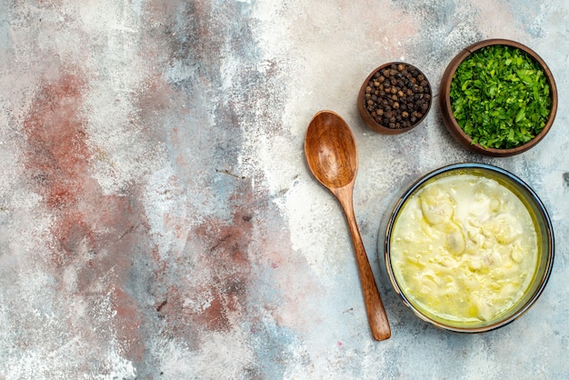 Vista superior tazones de sopa de bolas de masa hervida dushbara con cuchara de madera de pimienta verde sobre superficie desnuda con espacio de copia