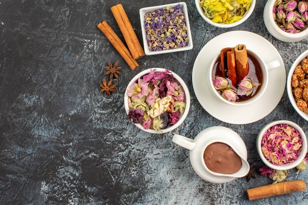 Foto gratuita vista superior de té de hierbas con chocolate derretido y flores secas en el lado izquierdo del suelo gris