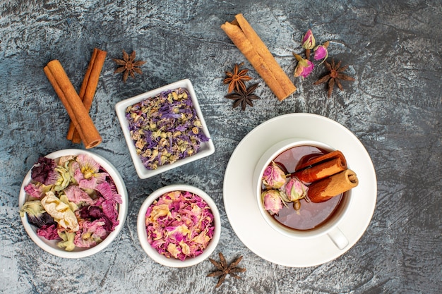 Vista superior de té de hierbas con flores secas y anís y canela sobre fondo gris