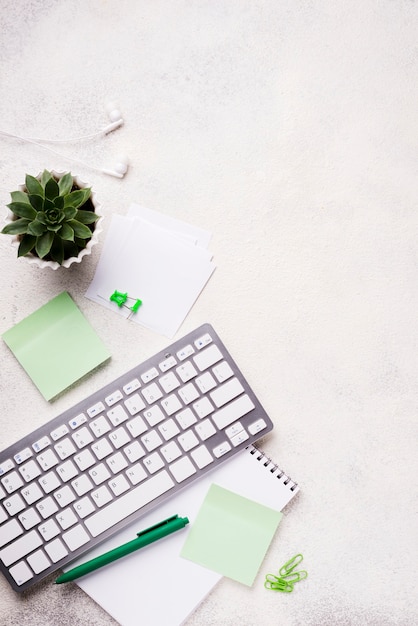 Vista superior del teclado en el escritorio con plantas suculentas y notas adhesivas