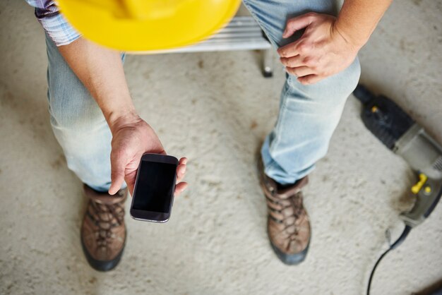 Vista superior del teléfono móvil utilizado por el trabajador manual