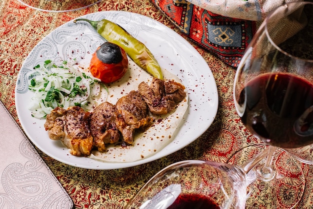 Vista superior tika kebab en pan de pita con verduras y cebollas a la parrilla y una copa de vino