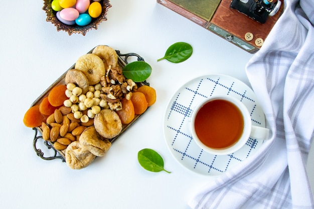 Vista superior de un tipo de nueces con albaricoques secos e higos secos en una bandeja con una taza de té