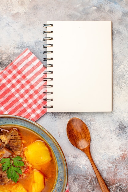 Foto gratuita vista superior de la toalla de cocina de sopa bozbash una cuchara de madera un cuaderno sobre fondo desnudo