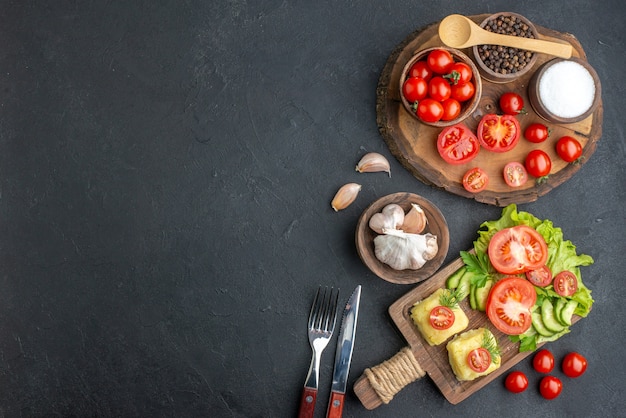 Vista superior de todo el corte de verduras frescas y especias sobre tabla de madera cubiertos de toalla blanca juego de queso sobre superficie negra