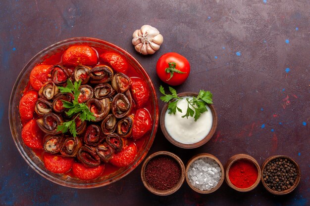 Vista superior de tomates y berenjenas de harina de verduras cocidas con condimentos en la superficie oscura