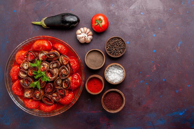 Vista superior de tomates y berenjenas de harina de verduras cocidas con condimentos en la superficie oscura