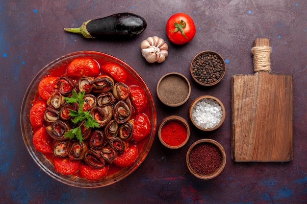 Vista superior de tomates y berenjenas de harina de verduras cocidas con condimentos en la superficie oscura