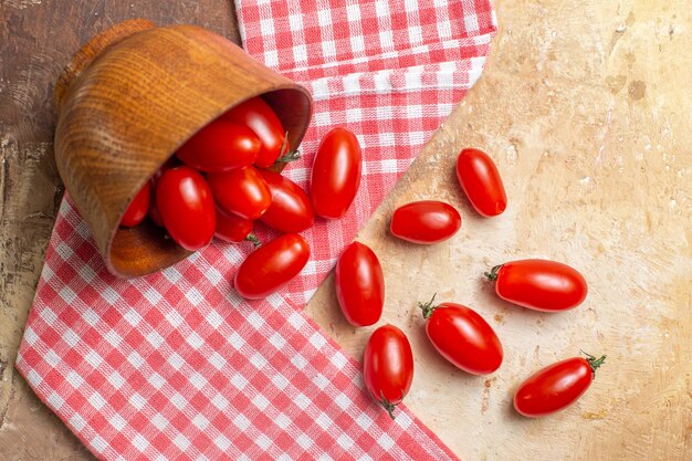 Vista superior de tomates cherry esparcidos del cuenco una toalla de cocina sobre fondo ámbar