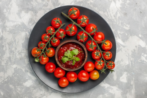 Vista superior de tomates cherry frescos dentro de la placa sobre superficie blanca
