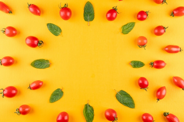 Vista superior de tomates cherry y menta en superficie amarilla con espacio de copia