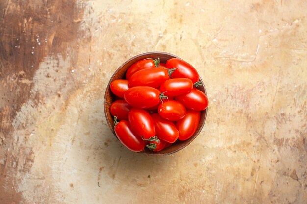 Vista superior de tomates cherry en un tazón de madera sobre fondo ámbar