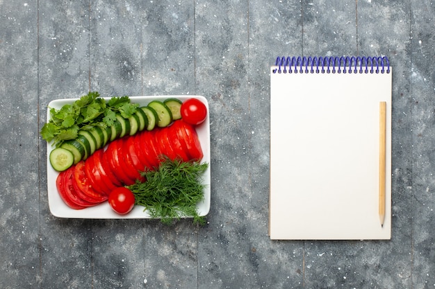 Foto gratuita vista superior tomates frescos en rodajas ensalada de elegante diseño en escritorio gris