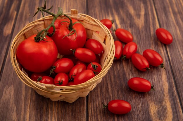 Vista superior de tomates frescos rojos en un balde en una pared de madera