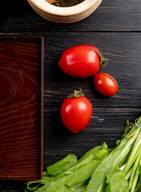 Vista superior de tomates y hojas de menta verde con bandeja sobre superficie de madera