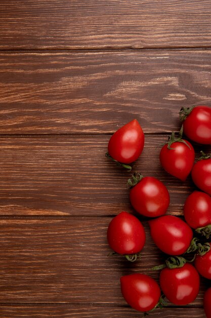 Vista superior de tomates en el lado derecho y superficie de madera con espacio de copia