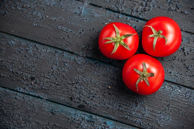 Vista superior de los tomates en la mesa tres tomates maduros rojos en la mesa de madera gris