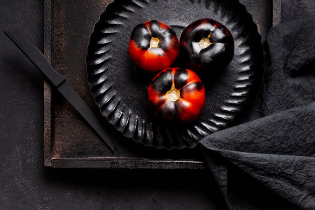 Vista superior de tomates negros al horno pintados en placa