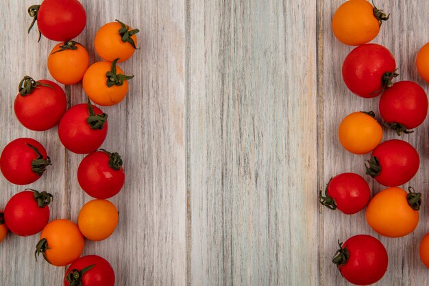 Vista superior de tomates orgánicos rojos y naranjas aislados en una pared de madera gris con espacio de copia