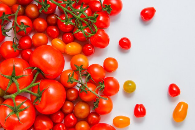 Vista superior de tomates pequeños y grandes sobre fondo blanco. horizontal