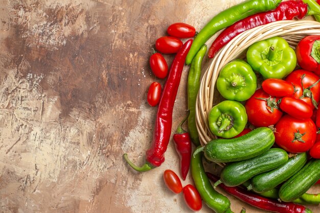 Vista superior de tomates pimientos verdes y rojos en verduras cesta de mimbre sobre fondo ámbar