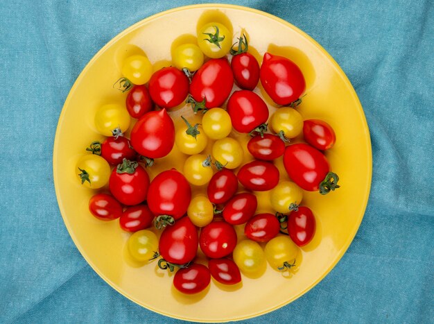 Vista superior de tomates en placa sobre superficie de tela azul