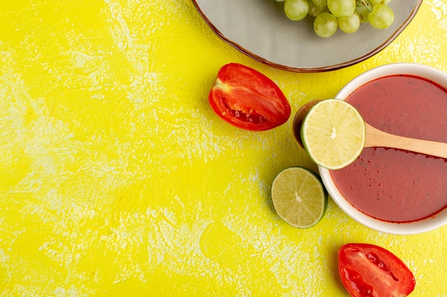 Vista superior de tomates en rodajas con limón sobre mesa amarilla, frutas de alimentos vegetales