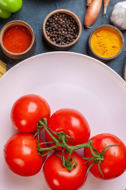Foto gratuita vista superior de tomates rojos con condimentos de verduras de pasta cruda y huevos en la mesa oscura