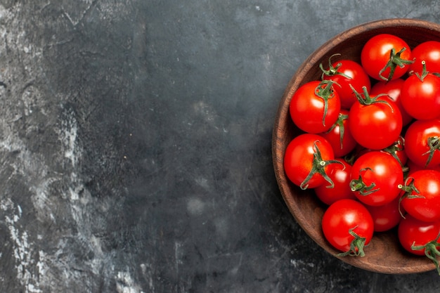 Vista superior de tomates rojos frescos dentro de la placa sobre fondo oscuro
