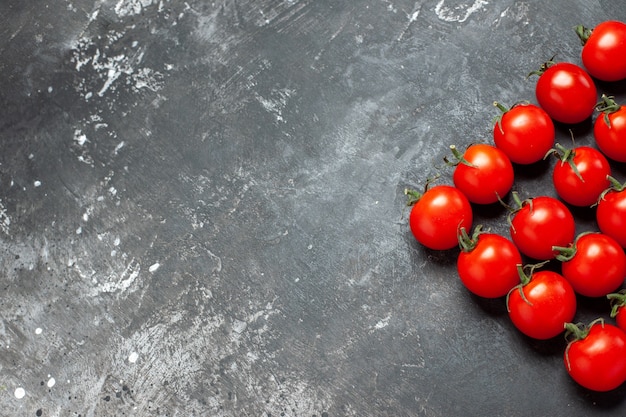 Vista superior de tomates rojos frescos forrados sobre fondo claro-oscuro